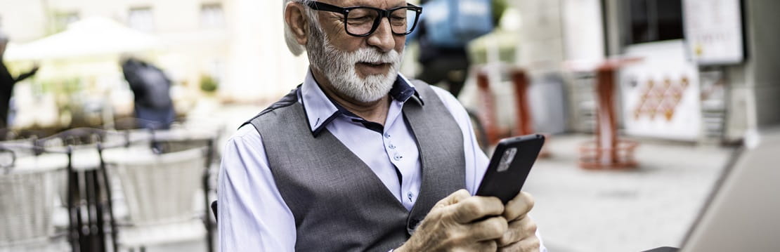 Senior businessman in a cafe looking at his smart phone.